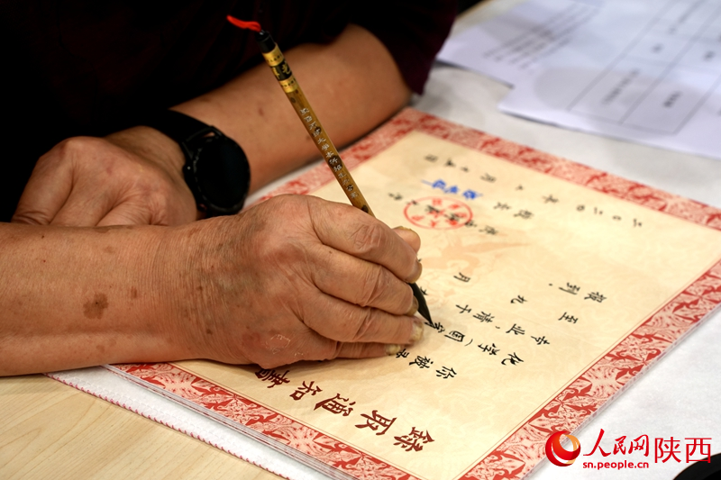 退休教師用毛筆為今年新生手寫錄取通知書。人民網(wǎng)記者 賈凱璐攝
